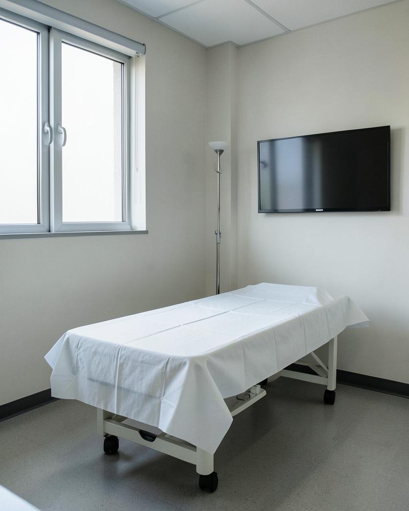 Outpatient clinic exam room with an exam table and wall screen